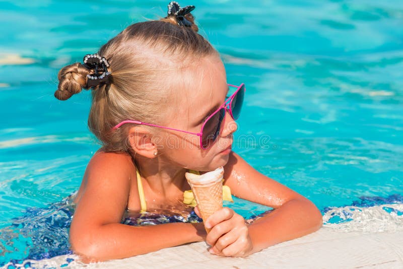 On a sunny day the girl in sunglasses with ice cream relaxing in the pool