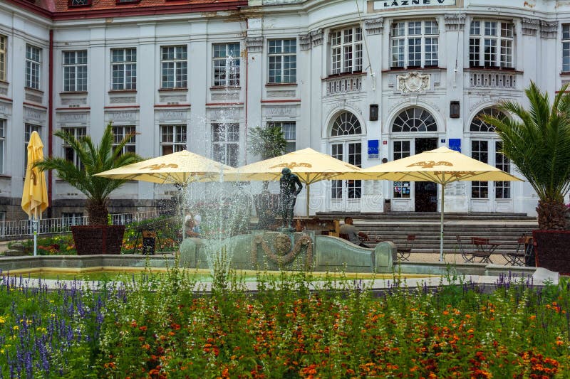 Sunny day in the great Czech spa town Karlovy Vary with fountain and yellow umbrellas .