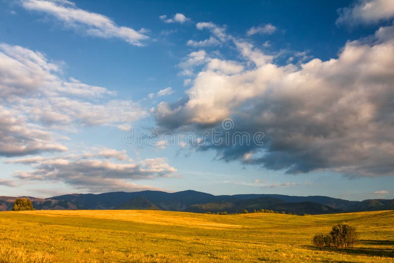 Sunny landscape with mountains and blue sky with clouds .