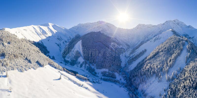 Sunny winter day in the snow-covered tyrolean mountains with a small mountain village and forest near bichlbach