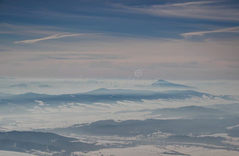 Sunlit blue ridges, misty valleys under cloud stripes in winter