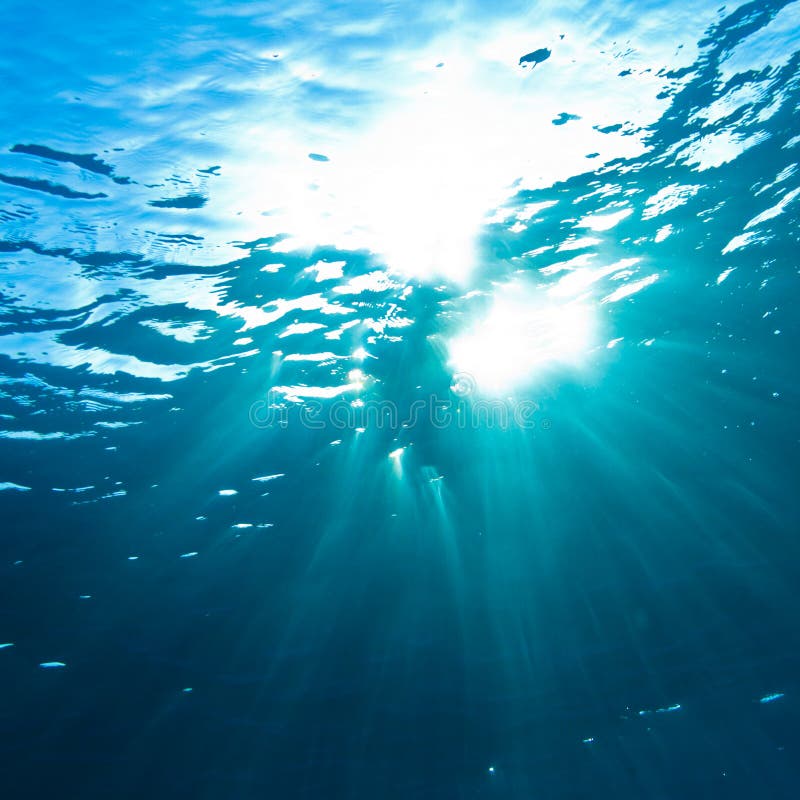 Abstracto escenario rayos de sol común a través de Agua superficie en profundo azul el mar.