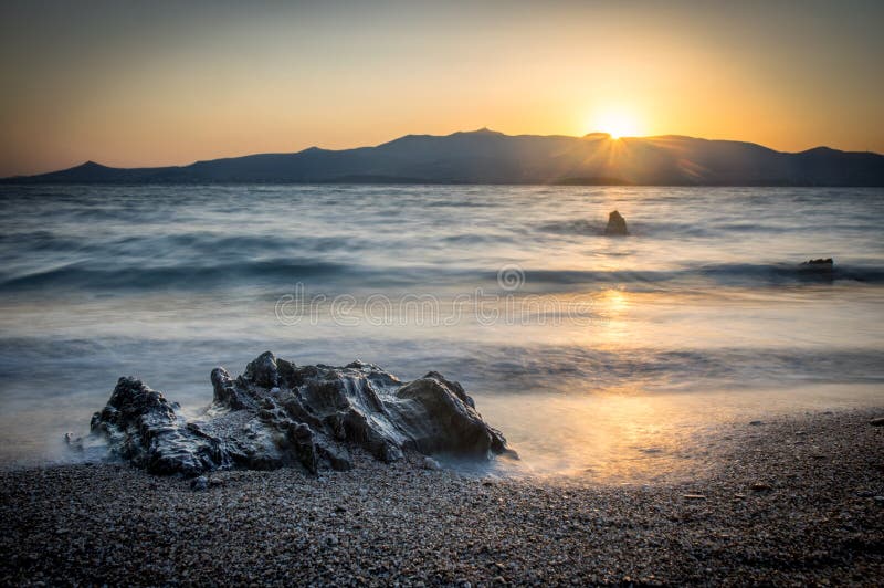 Sunrise on Antiparos island, rock and beach in the foreground, Paros island in the background. Cyclades Greece stock image Sunrise on Antiparos island, rock and beach in the foreground, Paros island in the background. Cyclades Greece stock image
