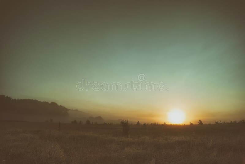 Sunrise in June in a Hilly Valley Against a Grassy Meadow Stock Photo