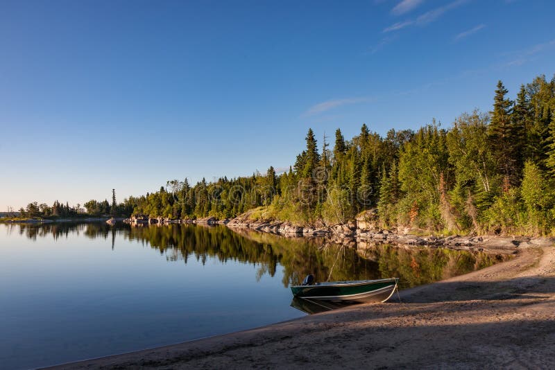 Sunrise on Nutimik Lake Manitoba. A boat is grounded on the beach on Nutimik Lake in the scenic Whiteshell area of eastern Manitoba, Canada stock photos Sunrise on Nutimik Lake Manitoba. A boat is grounded on the beach on Nutimik Lake in the scenic Whiteshell area of eastern Manitoba, Canada stock photos