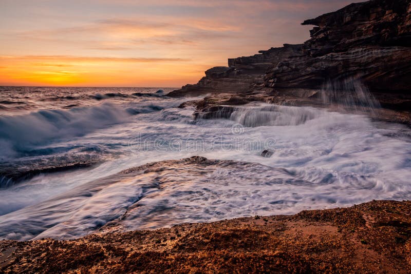Sunrise and ocean cascades along coastal rocks and headland royalty free stock photo Sunrise and ocean cascades along coastal rocks and headland royalty free stock photo