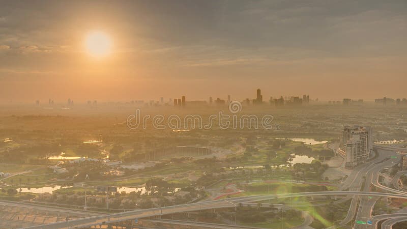 Sunrise over Golf course green lawn and lakes, villa houses behind it aerial . Village triangle and circle district. Top morning view from Dubai marina skyscraper. Sunrise over Golf course green lawn and lakes, villa houses behind it aerial . Village triangle and circle district. Top morning view from Dubai marina skyscraper.