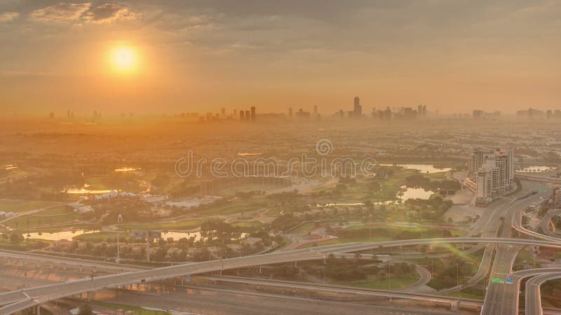 Sunrise over Golf course green lawn and lakes, villa houses behind it aerial timelapse. Village triangle and circle district. Top morning view from Dubai marina skyscraper. Sunrise over Golf course green lawn and lakes, villa houses behind it aerial timelapse. Village triangle and circle district. Top morning view from Dubai marina skyscraper.