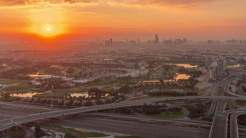 Sunrise over Golf course green lawn and lakes, villa houses behind it aerial timelapse. Village triangle and circle district. Top morning view from Dubai marina skyscraper. Sunrise over Golf course green lawn and lakes, villa houses behind it aerial timelapse. Village triangle and circle district. Top morning view from Dubai marina skyscraper.