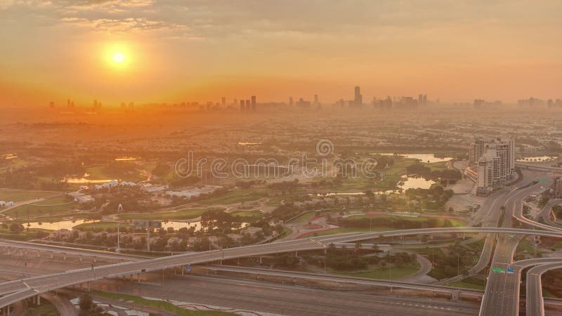 Sunrise over Golf course green lawn and lakes, villa houses behind it aerial timelapse. Village triangle and circle district. Top morning view from Dubai marina skyscraper. Sunrise over Golf course green lawn and lakes, villa houses behind it aerial timelapse. Village triangle and circle district. Top morning view from Dubai marina skyscraper.