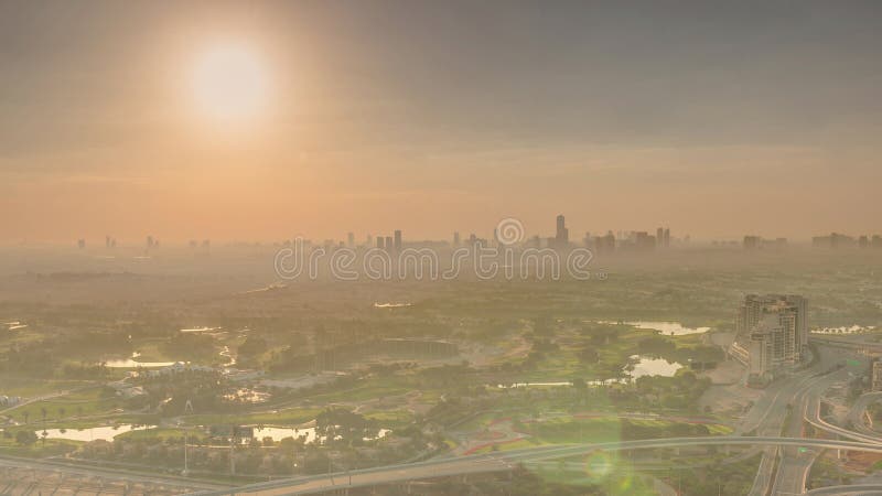 Sunrise over Golf course green lawn and lakes, villa houses behind it aerial. Village triangle and circle district. Top morning view from Dubai marina skyscraper. Sunrise over Golf course green lawn and lakes, villa houses behind it aerial. Village triangle and circle district. Top morning view from Dubai marina skyscraper.