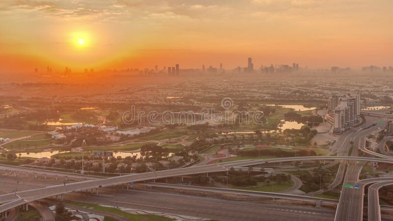Sunrise over Golf course green lawn and lakes, villa houses behind it aerial timelapse. Village triangle and circle district. Top morning view from Dubai marina skyscraper. Sunrise over Golf course green lawn and lakes, villa houses behind it aerial timelapse. Village triangle and circle district. Top morning view from Dubai marina skyscraper.