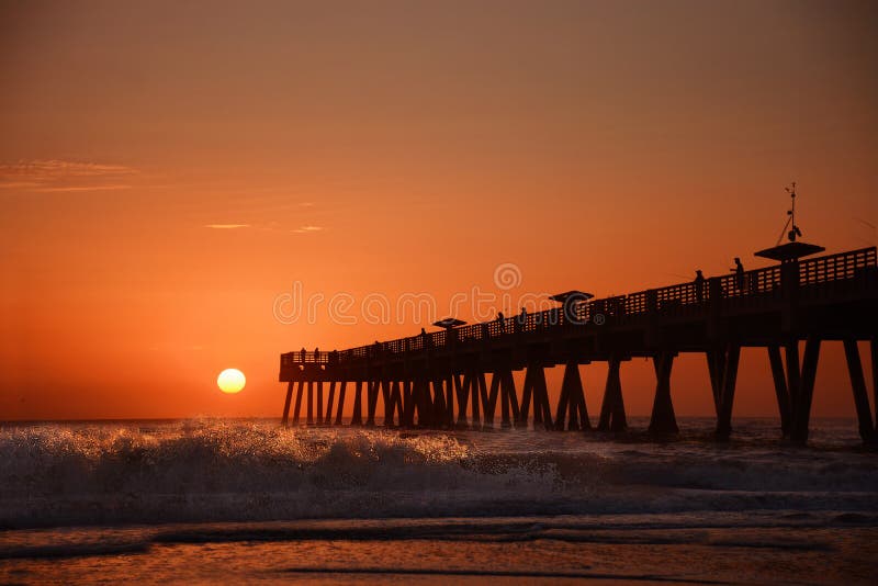 Sunrise over horizon and fishing pier.