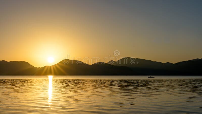 Sunrise over mountains and lake with canoeist