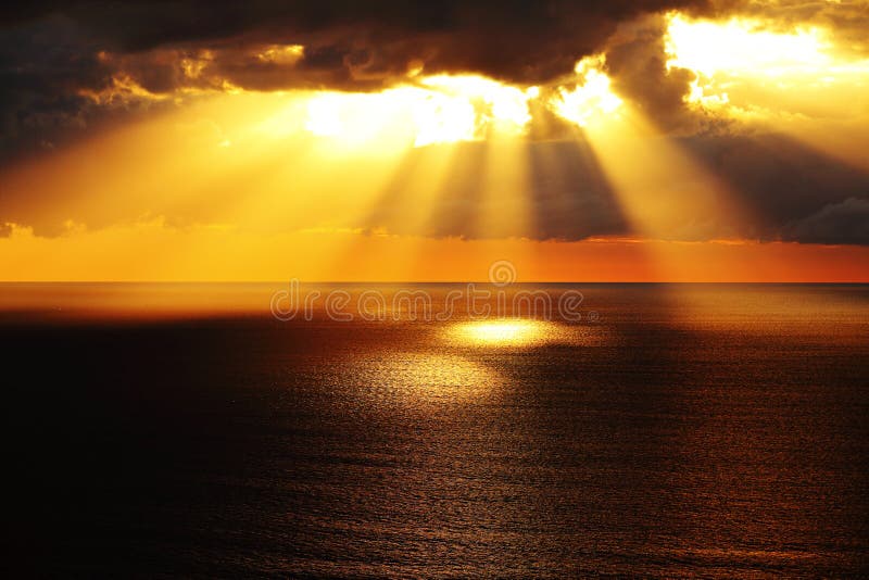 Golden sunlight through dark clouds over ocean