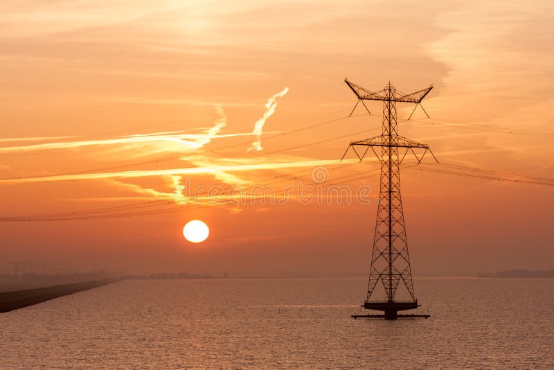 Sunrise over the sea with an electricty pylon