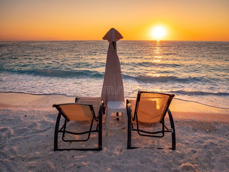 Sunrise with sun chairs and umbrella on the seashore at Marble Beach on the Greek Island Thasos in the Aegean Sea