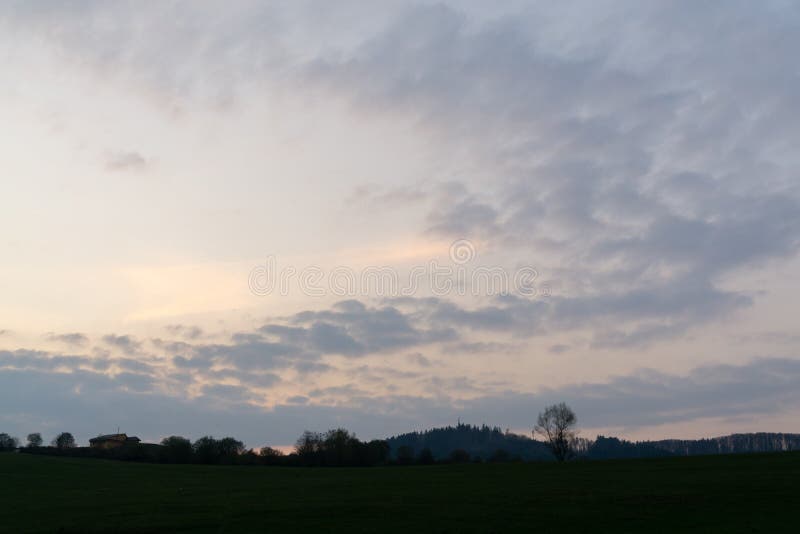 Východ nebo západ slunce nad kopci a loukou.