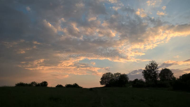 Východ alebo západ slnka nad kopcami a lúkou.