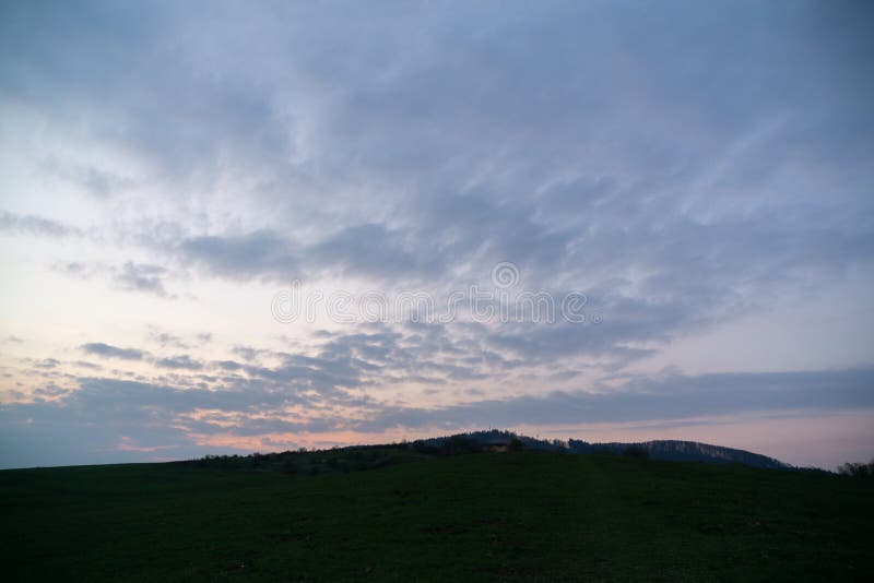 Východ nebo západ slunce nad kopci a loukou.