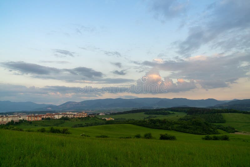 Východ nebo západ slunce nad kopci a loukou.