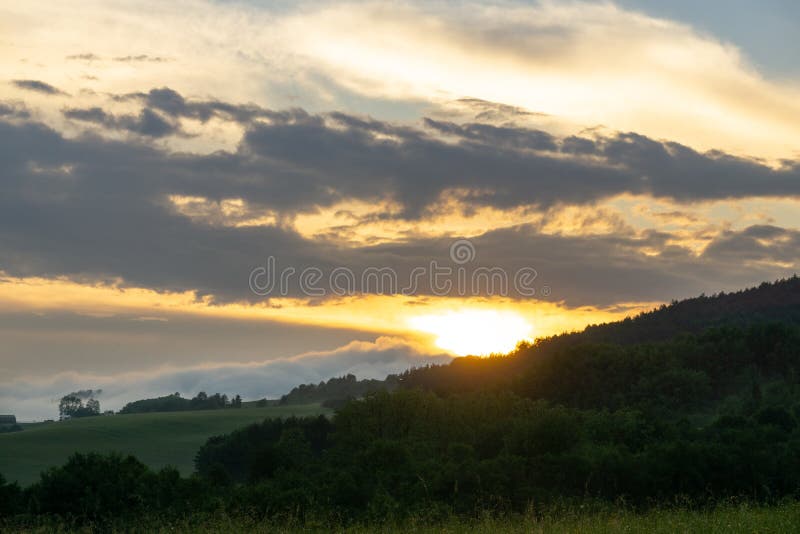 Sunrise or sunset over the hills and meadow.