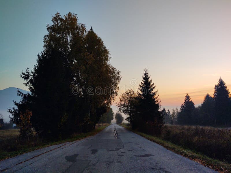 Východ nebo západ slunce nad kopci a loukou.