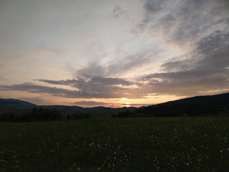 Sunrise or sunset over the hills and meadow.
