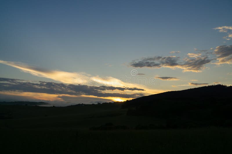 Sunrise or sunset over the hills and meadow.