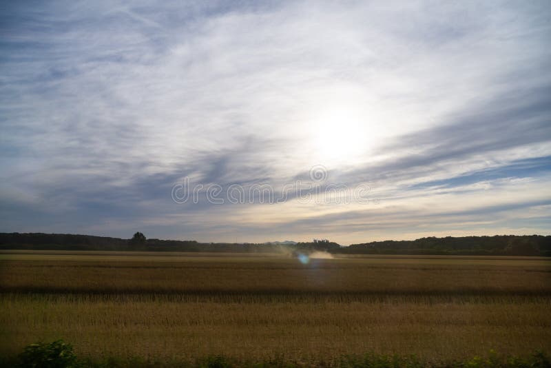 Východ nebo západ slunce nad kopci a loukou.