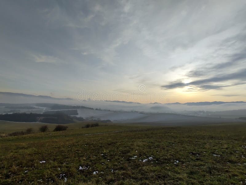 Sunrise or sunset over the hills and meadow.