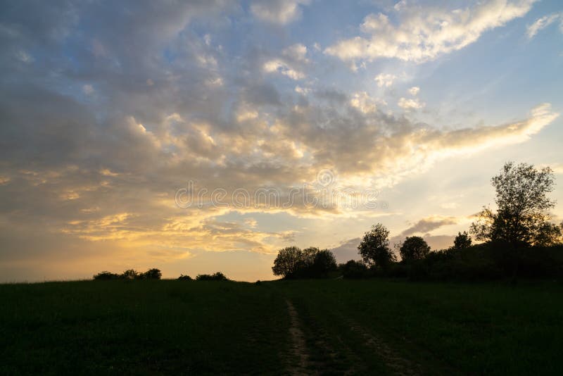 Východ nebo západ slunce nad kopci a loukou.