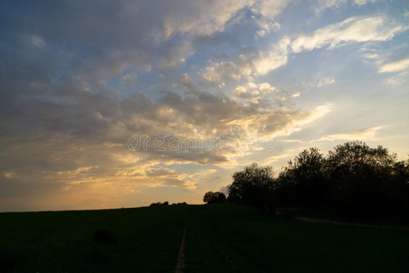 Východ nebo západ slunce nad kopci a loukou.