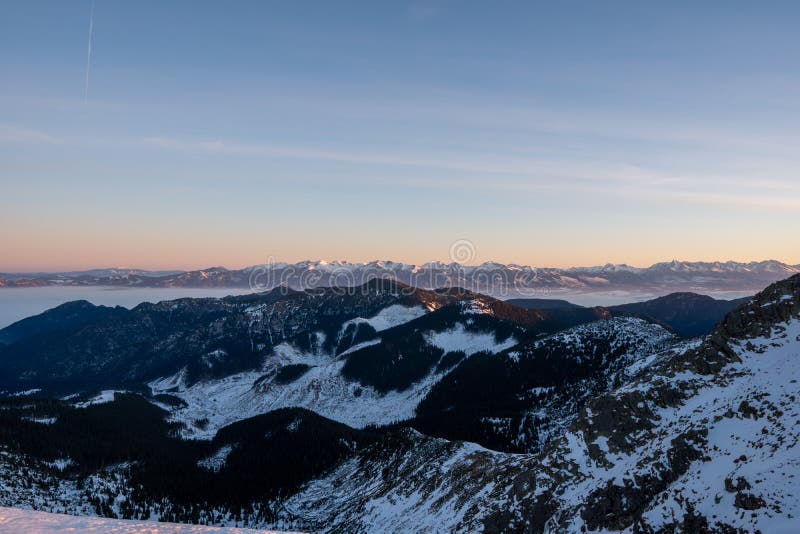 Východ slnka v zimných horách s jasnou oblohou s výhľadom na vysoké tatry v pozadí, slovensko nízke tatry, dumbier