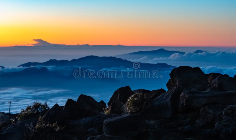 Sunset on Ancient Volcana Mountain Top Haleakala Hawaii. Standing above the clouds at twelve thousand feet where the sun rises and sets above the clouds is a stock images Sunset on Ancient Volcana Mountain Top Haleakala Hawaii. Standing above the clouds at twelve thousand feet where the sun rises and sets above the clouds is a stock images