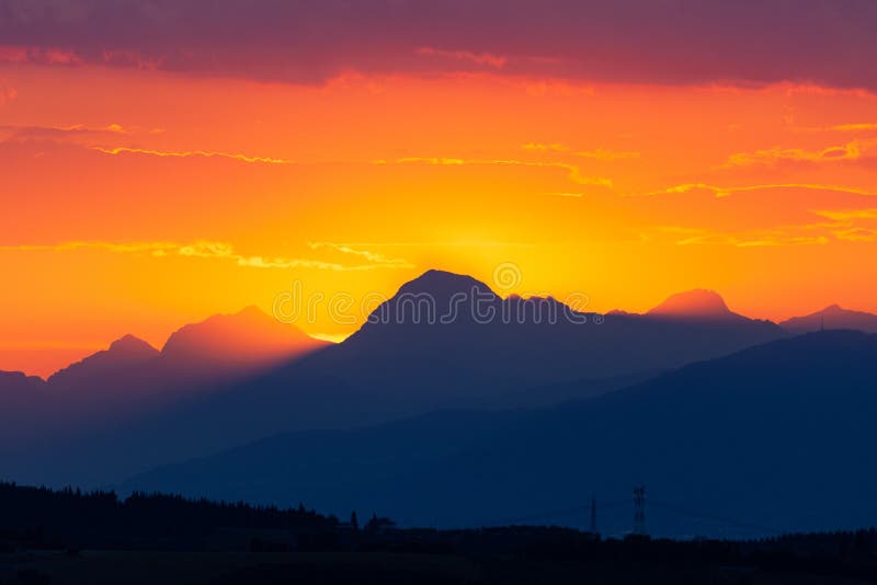 Slunce zapadá za vrcholky Apuane Alpách v Itálii.