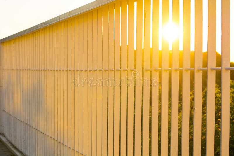 Sunset through the bars of the railing bridge stock images
