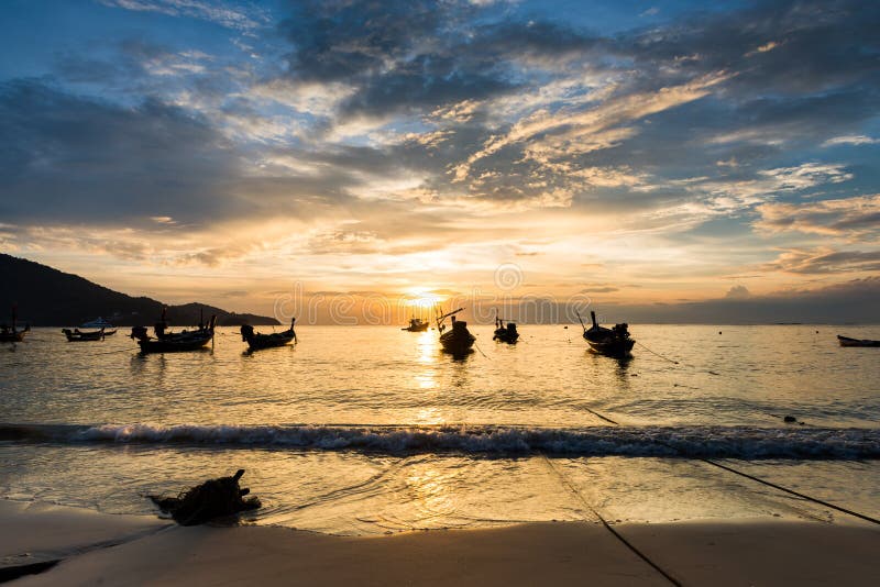 Sunset on the beach with fishing boat in Phuket.