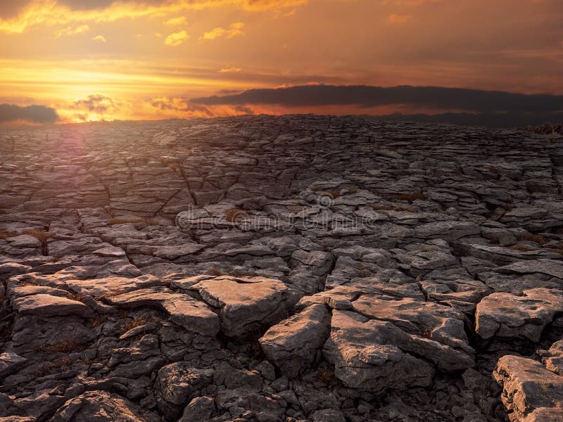 Sunset in Burren National Park, Dramatic sunset sky and sun flare, Rough stone terrain. Ireland. Warm colors