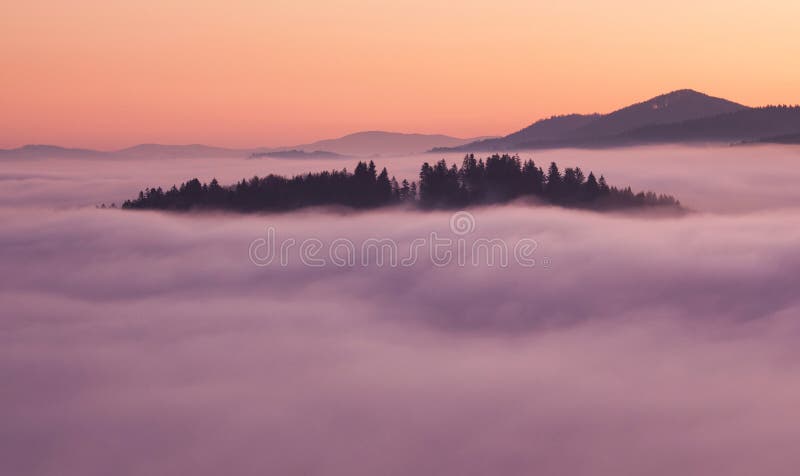 Sunset hidden behind clouds and fog over hills, bright yellow sun on colorful cloudscape, blue violet orange sky