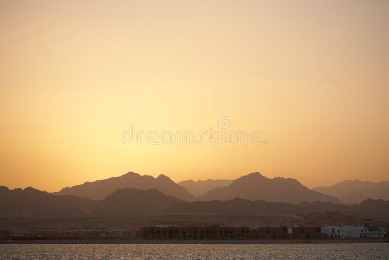 Sunset landscape - sea, mountains, yellow sky