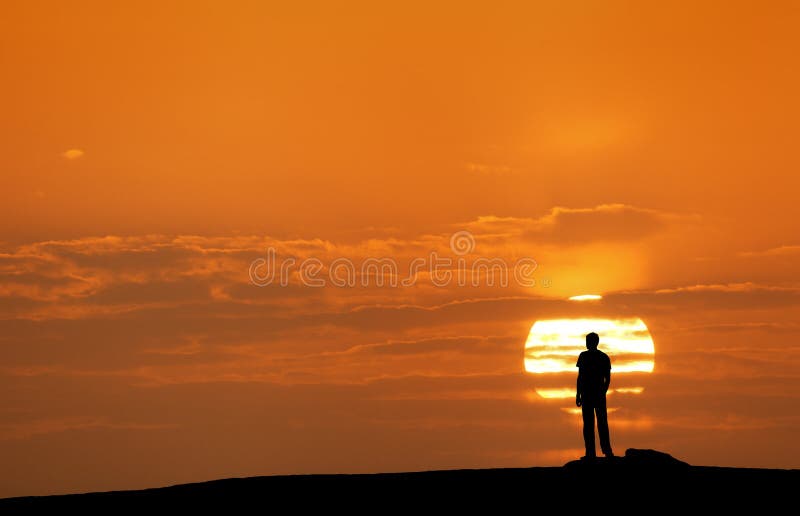 Sunset landscape with silhouette of a man with raised-up arms