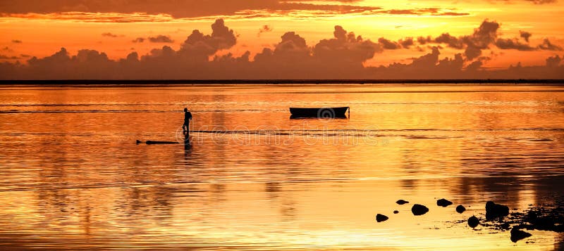 Sunset at Mauritius island with silhouette of unrecognizable fisherman going home after a day of fishing - Wanderlust and travel