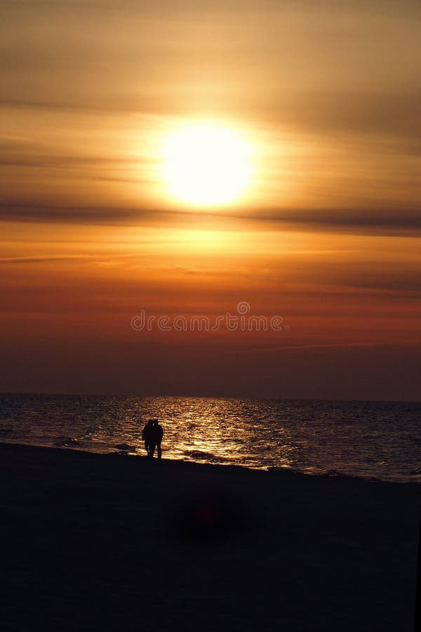 Sunset over the Baltic sea in Poland Europe with a couple of people in love on the beach