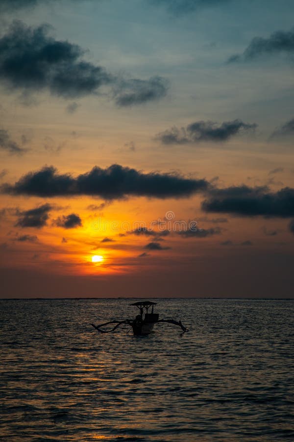 Sunset over calm ocean with balinese boat stock image Sunset over calm ocean with balinese boat stock image