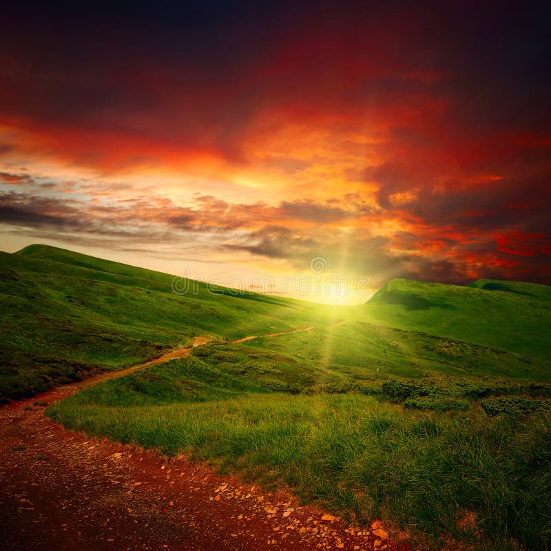 Parth attraverso un mistero prato di montagna all'orizzonte il tramonto, le nuvole.