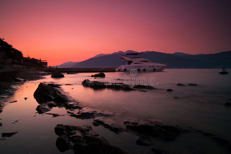 Sunset, rocks, sea and yacht