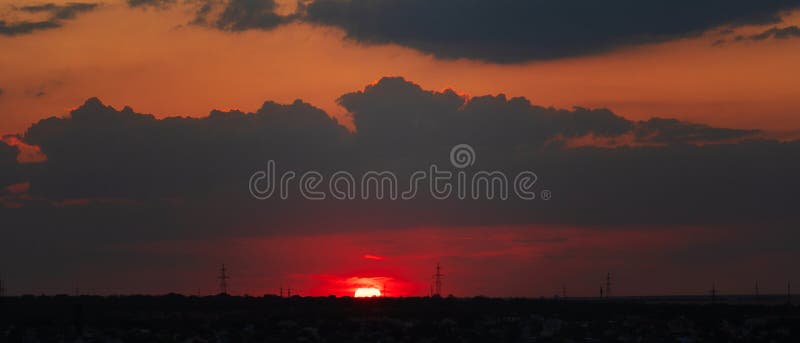 Sunset sun half below horizon with deep red sky and dark clouds stock photos