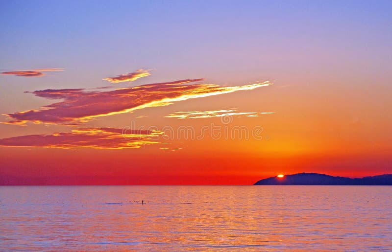 Sunset view of Santa Catalina Island with paddle boarders off Laguna Beach, California.