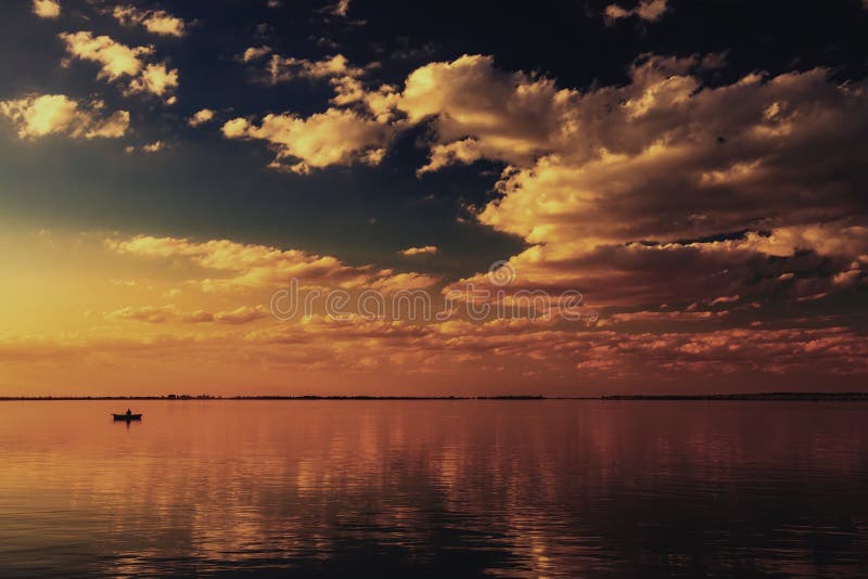 Sunset in the Volga River Delta. A riverscape with a fishing boat. Astrakhan Region, Russia.